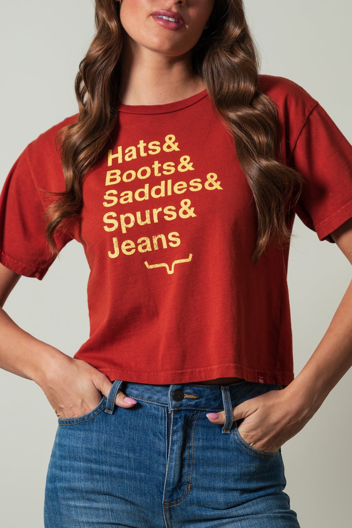 Kimes Ranch Hats & Boots shirt in Burnt Red with a gold screen print reading "Hats & Boots & Saddles & Spurs & Jeans"; #color_burnt red