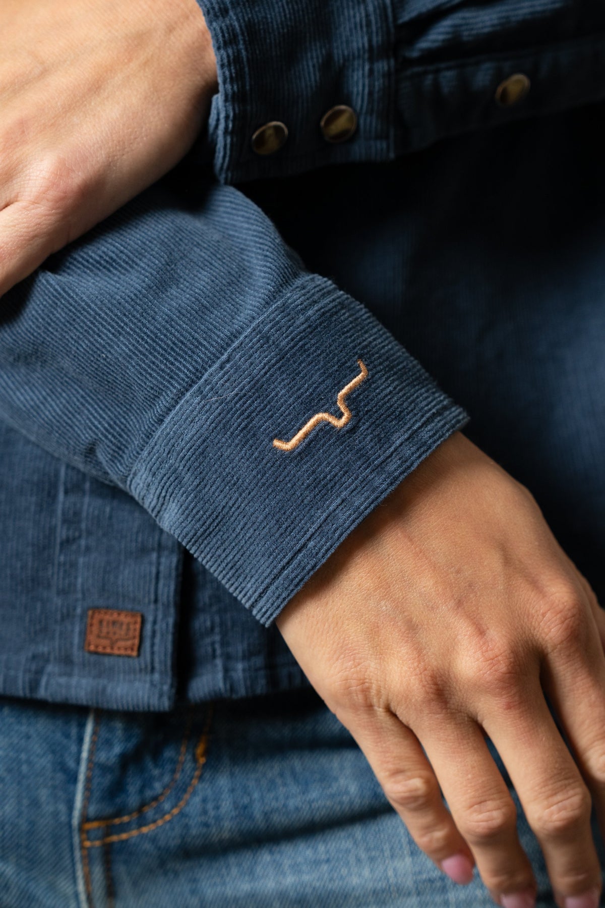 Kimes Ranch Lehi top in Dark Blue showing corduroy sleeve cuff with tan embroidered logo and leather brand patch