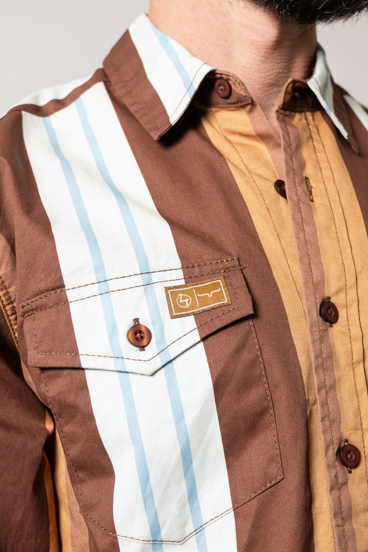 Kimes Ranch ZT Noxx long sleeve dress shirt in Dark Brown with tan and blue vertical stripes, chest pocket, and logo patch