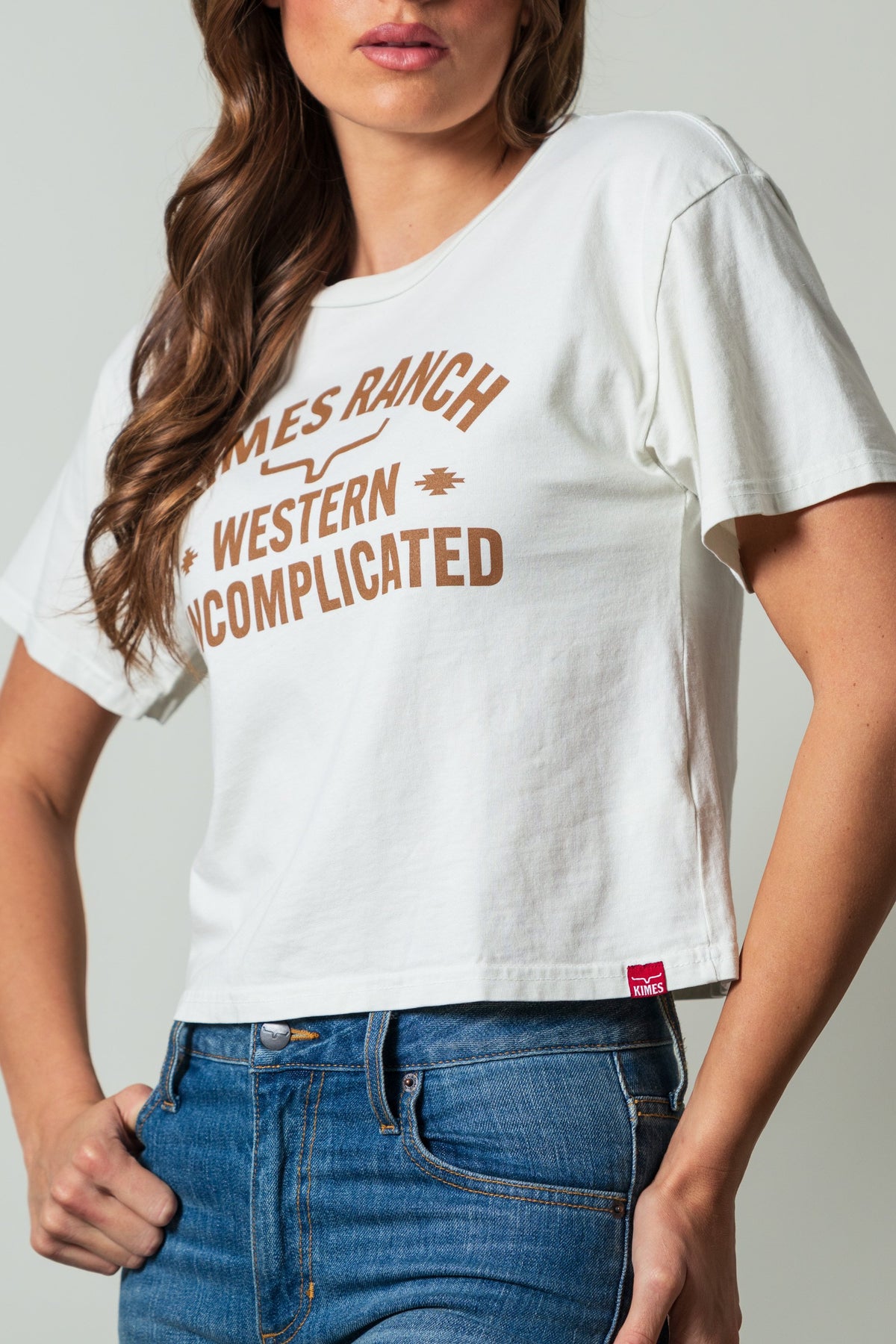 Kimes Ranch Cavell Natural shirt featuring a 'Western Uncomplicated' print with a Kimes Ranch logo at the center