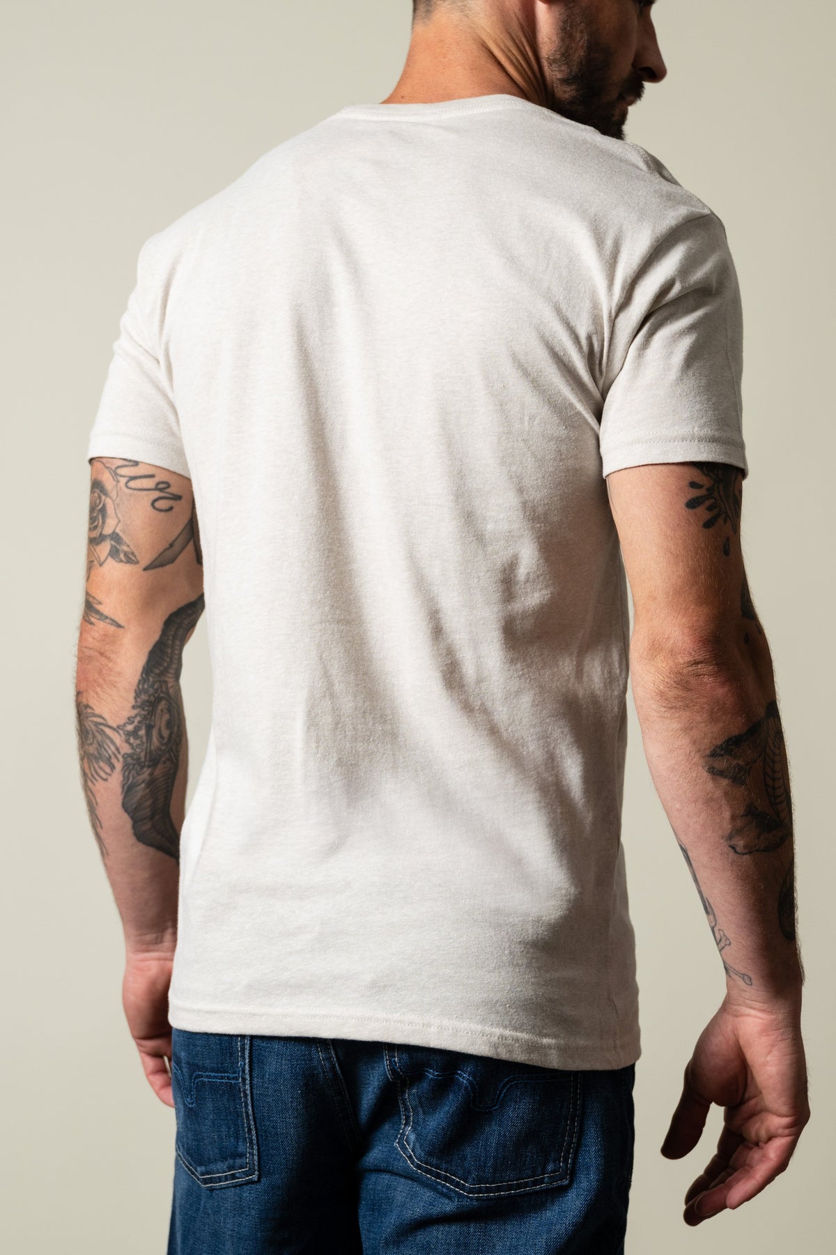 Kimes Ranch Davona Dale shirt in sand, short sleeve crew neck, plain back with ribbed cuffs, model viewed from behind; #color_sand