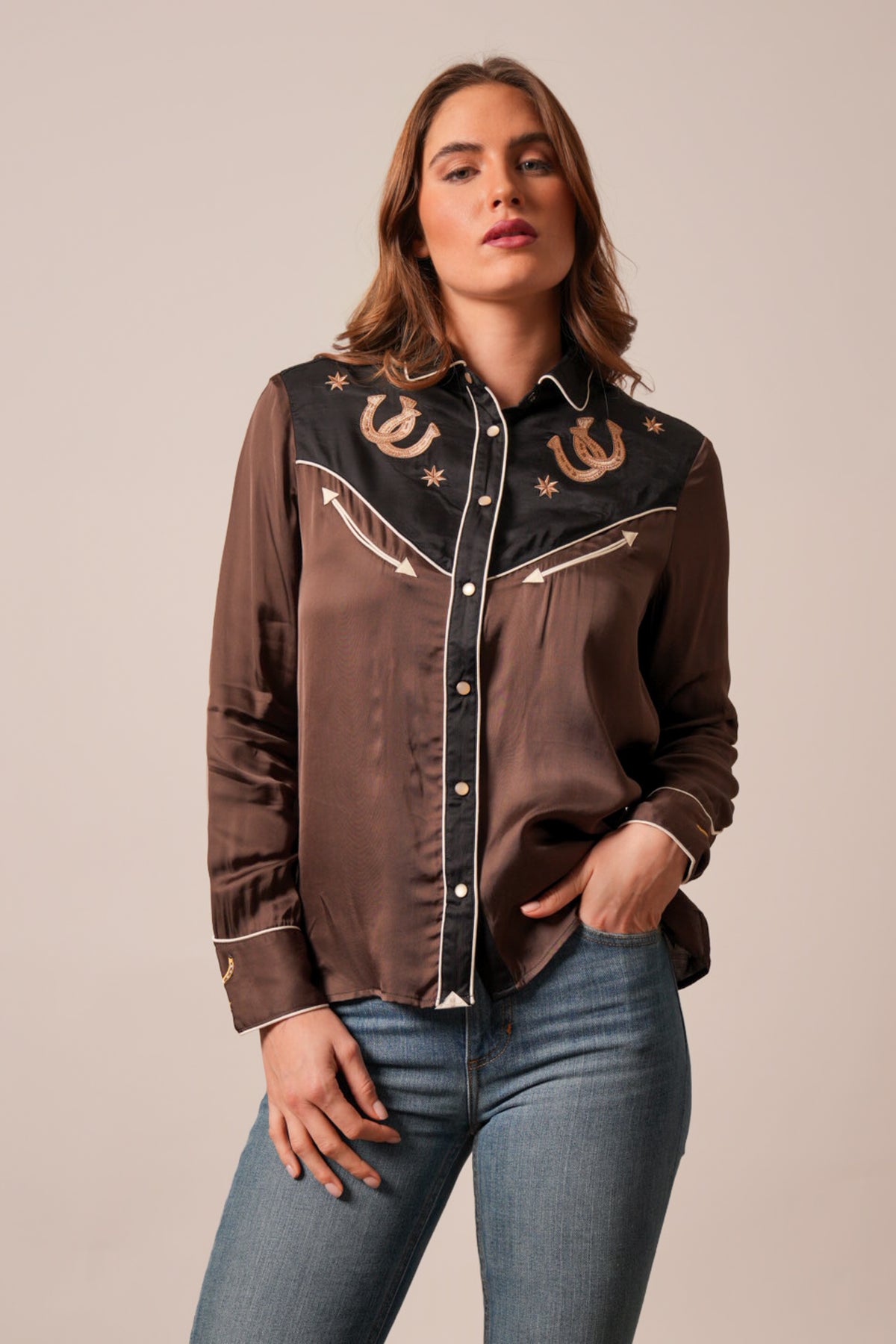 Kimes Ranch Merada black top featuring embroidered horseshoes on a black yoke with brown body, white piping and long sleeves