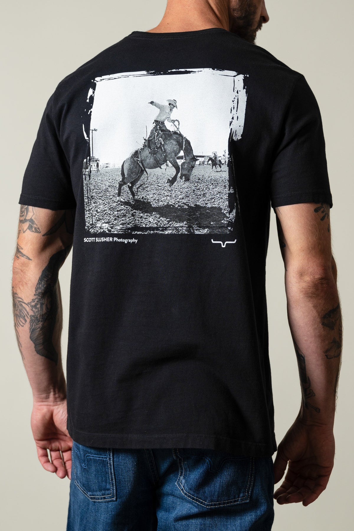 Kimes Ranch SS Bronc Ride shirt, black, back view showing cowboy bucking bronc graphic with SCOTT SLUSHER Photography text; #color_black
