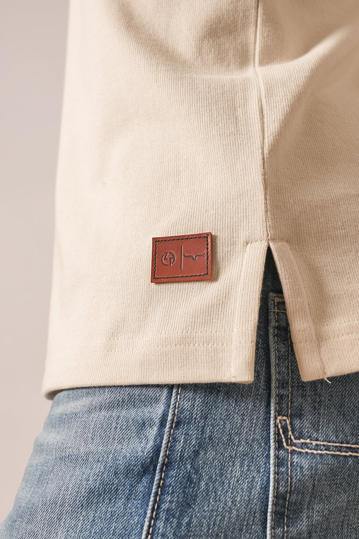 Kimes Ranch ZT Rugger polo in Natural, featuring the Kimes Ranch logo on a leather patch at the hem detail
